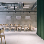 De Hoorn | Leuven - meeting room. Green curtain, industrial lightning. Light wooden chairs.