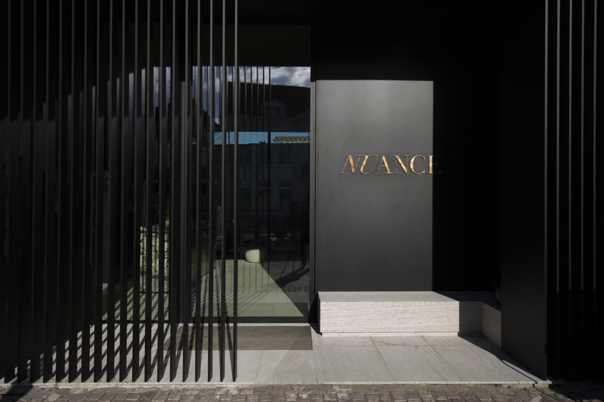 Nuance | Duffel - outside entree. Window and black wall with golden letters.